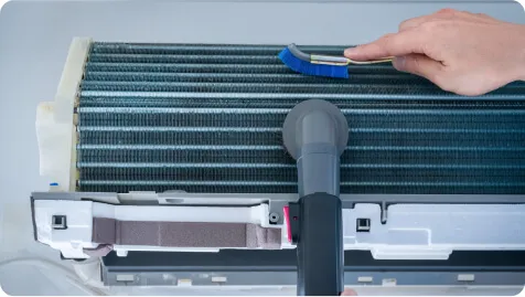 STEP2 ホコリの除去：熱交換器のフィンをブラシとバキュームでホコリ取りする様子